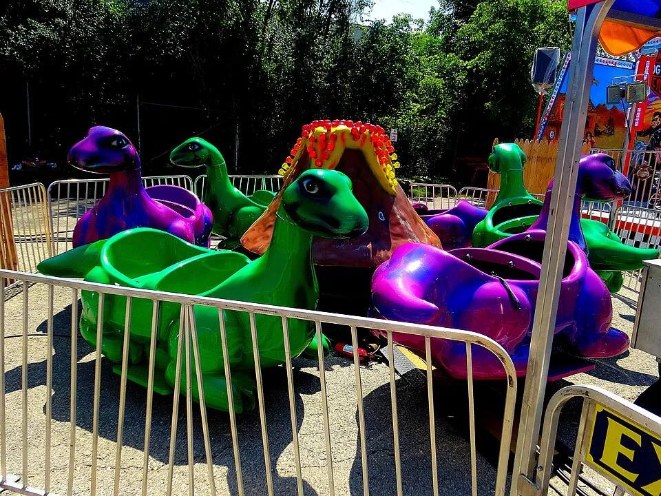 Purple and green dinosaur seats on the Flying Dinos kiddie ride — school carnival ride rental Los Angeles