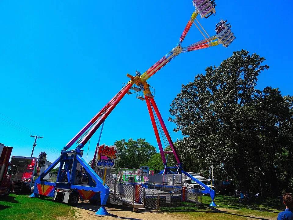 Freak Out pendulum thrill ride swinging high against a blue sky — fair ride rental Los Angeles